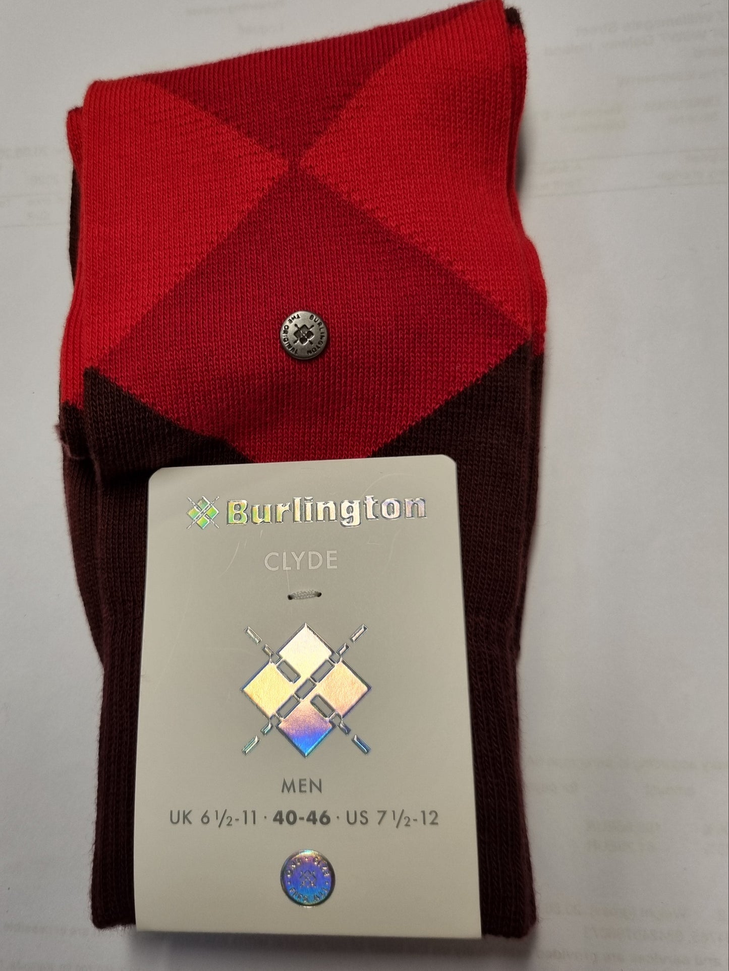 A pair of folded Burlington Clyde men's dress socks in a red and dark brown argyle pattern, with a white paper tag attached showing the brand and sizing information.